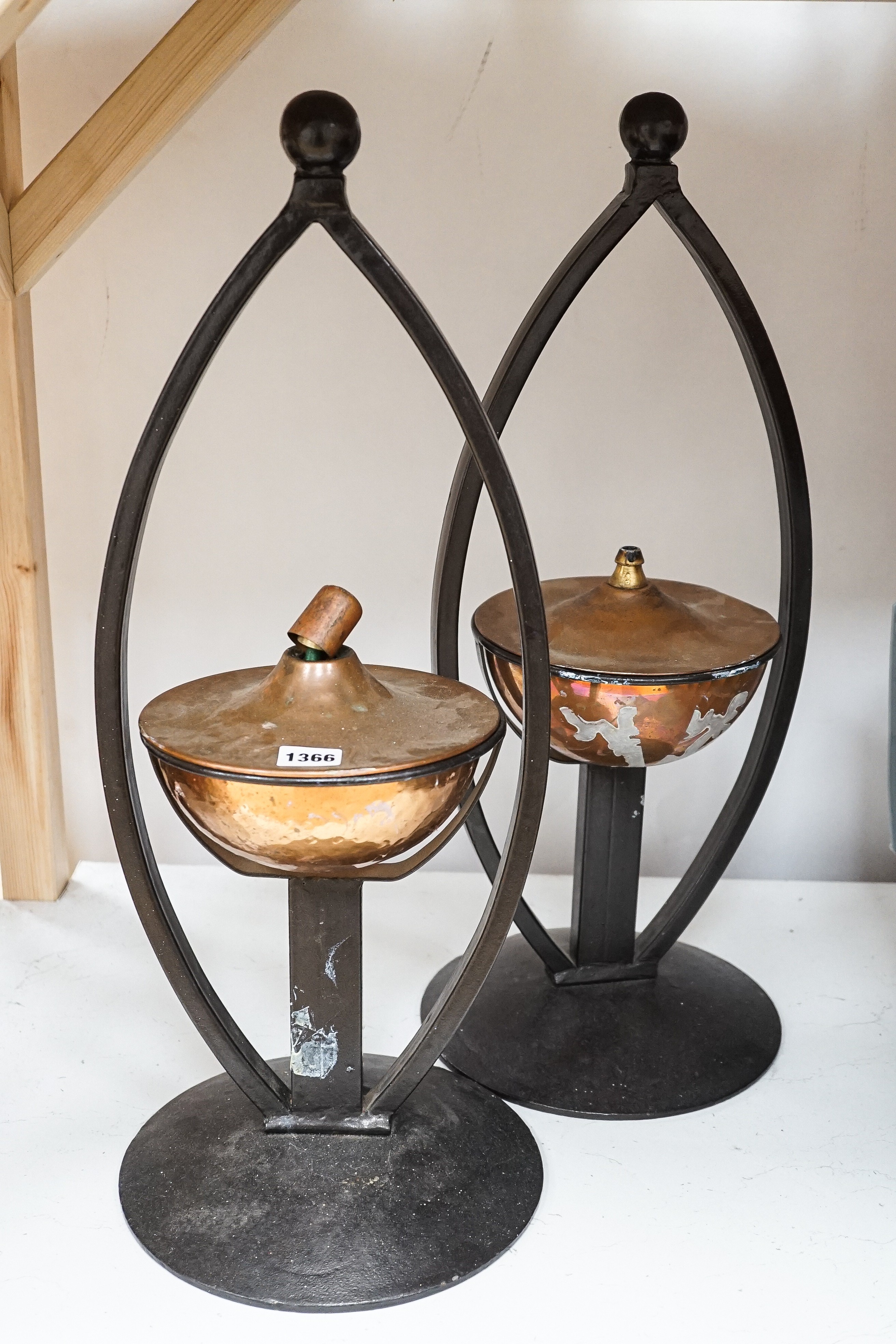 A pair of decorative copper lamps in arched mounts, 61 cms high.